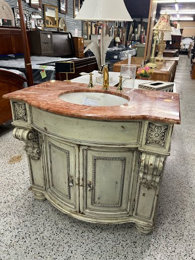 An elegant Stafford commode vanity with a marble top, wooden body painted in a shabby chic style, with ornate details and a matching mirror.
